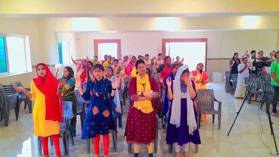 The congregation standing in worship with hands raised while the service is recorded